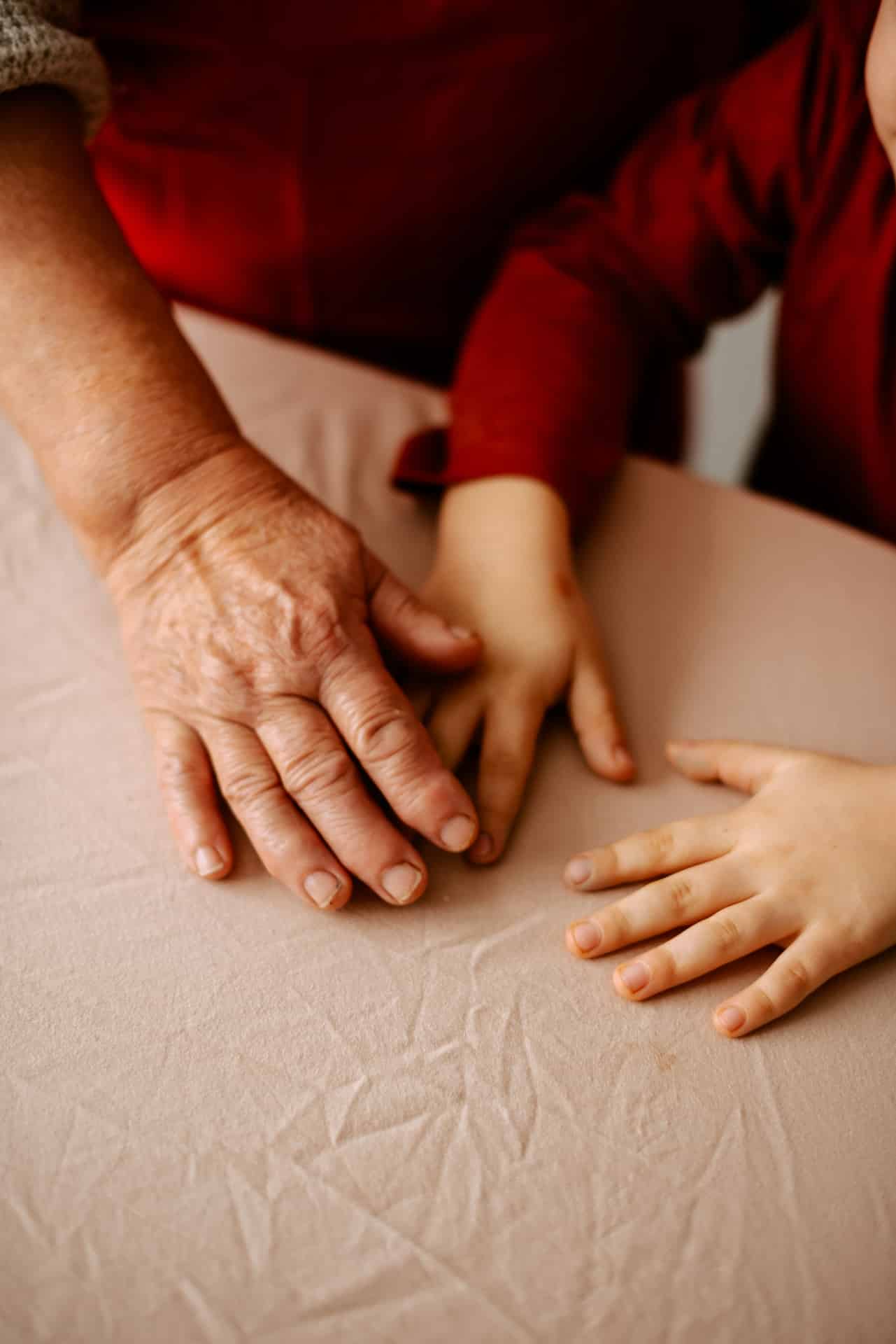 Hands of an elder and a young child resting together